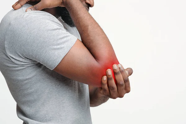 Обрізаний афро-чоловік натирає травмований лікоть — стокове фото