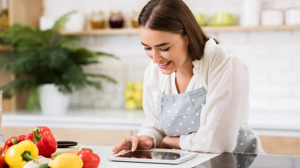 Auf der Suche nach Lieblingsrezept. Frau nutzt digitales Tablet in Küche — Stockfoto