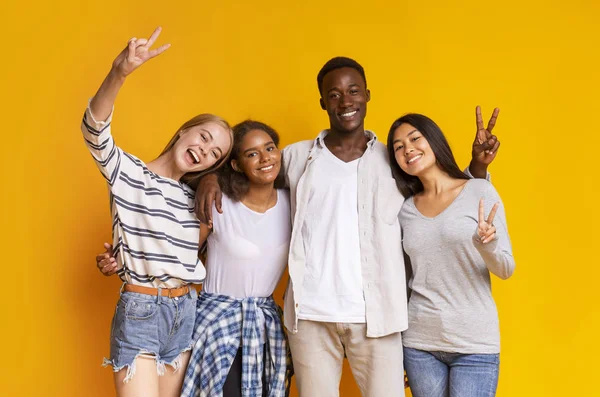 Беззаботные иностранные студенты веселятся на жёлтом фоне — стоковое фото