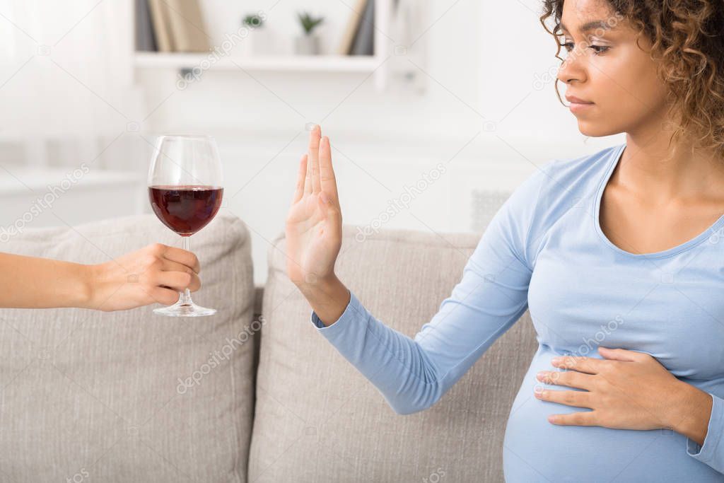 African-american pregnant woman rejecting alcohol at home