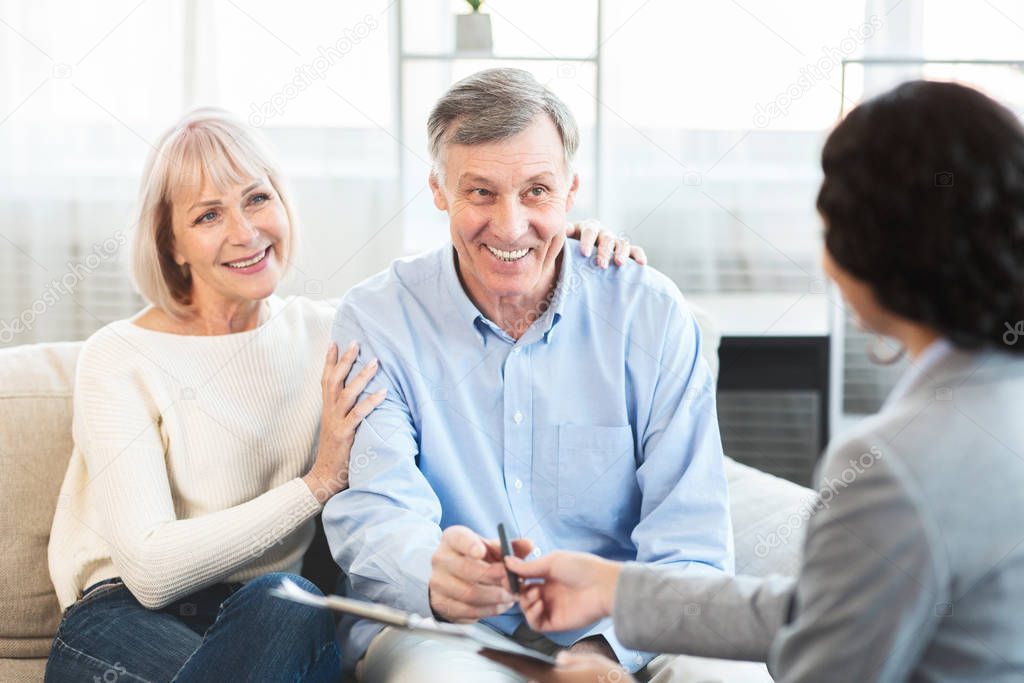 Happy mature couple talking to financial advisor at home