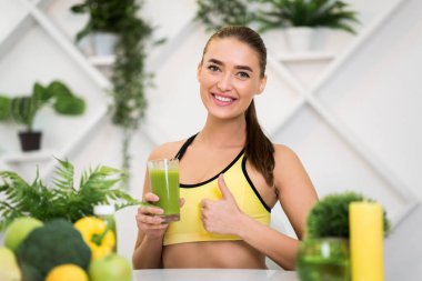 Smoothie bardağı tutan ve baş parmağını kaldıran...