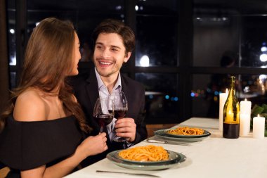 Mutlu bir erkek ve kadın romantik bir akşam yemeğinin tadını çıkarıyor.