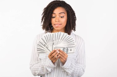 Heyecanlı afro genç beyaz arka planda para tutuyor.