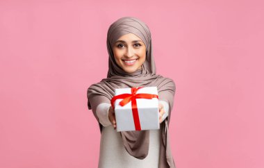 tesettürlü gülümseyen müslüman kadın kameraya hediye kutusu sunuyor