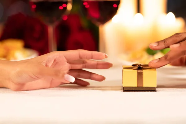 Mann schiebt Geschenkbox zu Freundin auf Restauranttisch, Nahaufnahme — Stockfoto