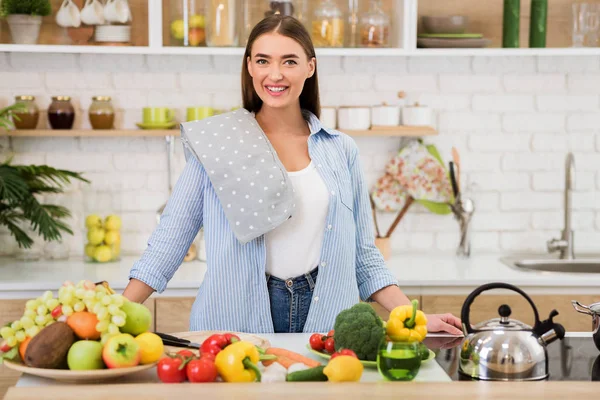 Happy woman standing near table with fresh vegetables and fruits — Stock Photo, Image