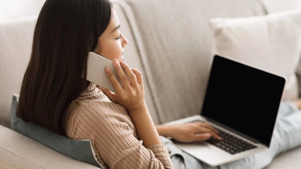 Girl websurfing on laptop and talking on phone at home — ストック写真