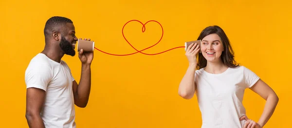 Loving black guy telling romantic words to girlfriend through tin phone — Stok Foto