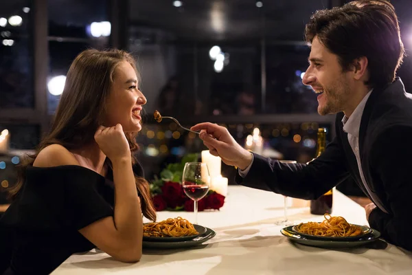 Wesoły mężczyzna karmi swoją dziewczynę na romantycznej randce — Zdjęcie stockowe