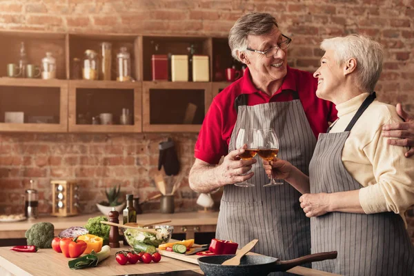 Felices personas mayores disfrutando de una copa de vino en la cocina —  Fotos de Stock