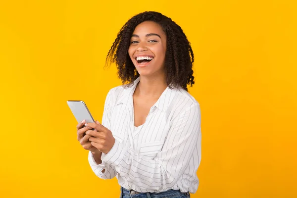 Mujer negra feliz usando el teléfono celular mirando la cámara — Foto de Stock