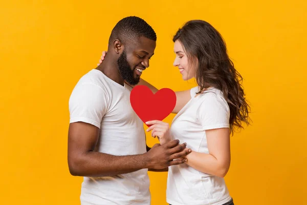 Портрет щасливої романтичної міжрасової пари з червоним паперовим серцем — стокове фото