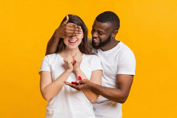 Romantischer Mann verdeckt Augen und schenkt seiner Freundin Verlobungsring — Stockfoto