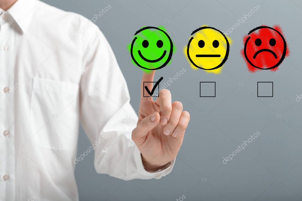 Hand ticking the happy smiley face icon over gray background