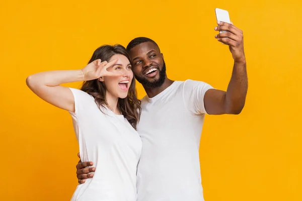 Веселая межрасовая пара делает селфи со смартфоном, веселится вместе — стоковое фото