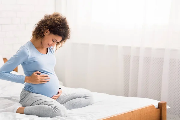 Pretty afro pregnant woman keeping hands on belly — ストック写真