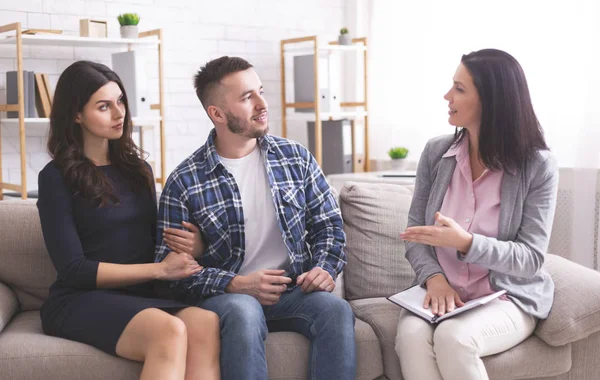 Millennial spouses talking with psychotherapist at office