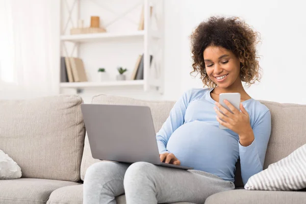 Niña embarazada afroamericana usando computadora portátil y teléfono celular — Foto de Stock