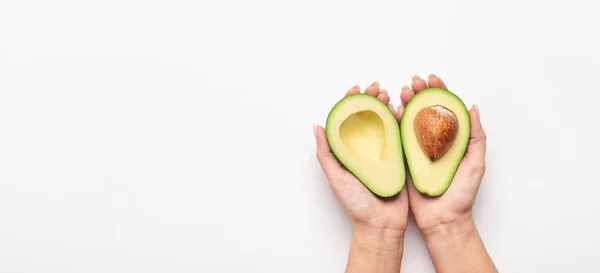 Frau, die in Palmen Avocado halbiert — Stockfoto