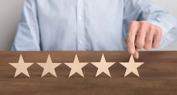 Consumidor colocando blocos de madeira de cinco estrelas na mesa — Fotografia de Stock