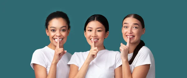 Tre ragazze multirazziali gesticolando dito sulle labbra Segno, Studio, Panorama — Foto Stock