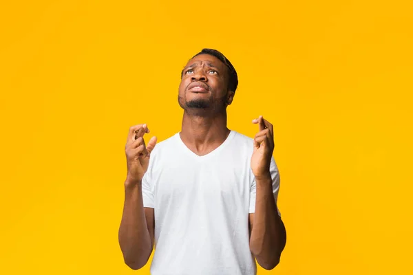 Afro-Amerikaanse man houdt vingers gekruist staande over gele achtergrond — Stockfoto