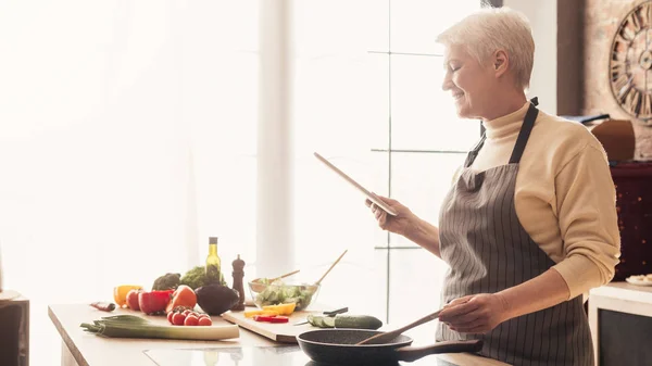 Seniorin nutzt digitales Tablet in Küche — Stockfoto