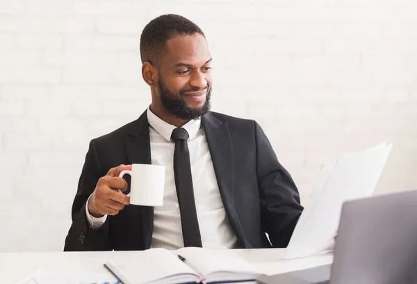 Alegre hombre de negocios bebiendo café, leyendo informes diarios —  Fotos de Stock