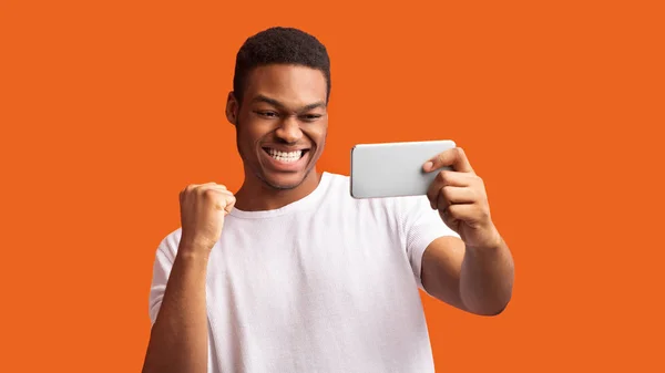Emocionado chico afro usando el teléfono celebrando el éxito — Foto de Stock