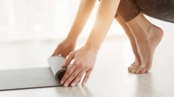 Weibliche Hände rollen Yogamatte nach Yogastunde — Stockfoto