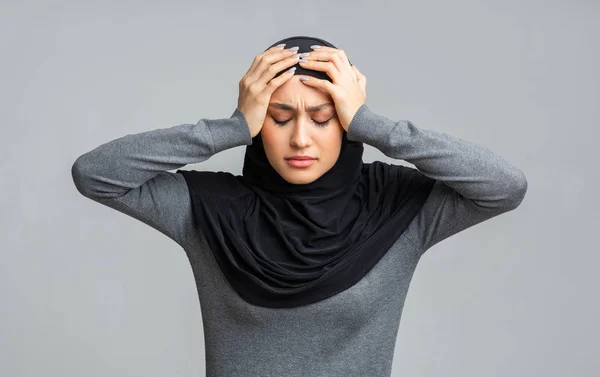 Depresso donna musulmana in hijab tenendo la testa in mano — Foto Stock