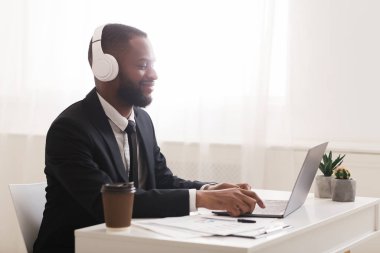 Ofiste çalışırken müzik dinleyen genç ve mutlu bir yönetici.