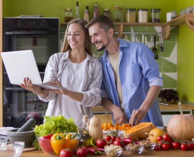 Mutfakta laptopta yemek tarifi bekleyen sevimli bir çift.