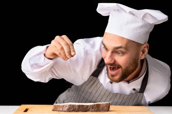 Chef Man koření losos steak stojící nad černým pozadím — Stock fotografie