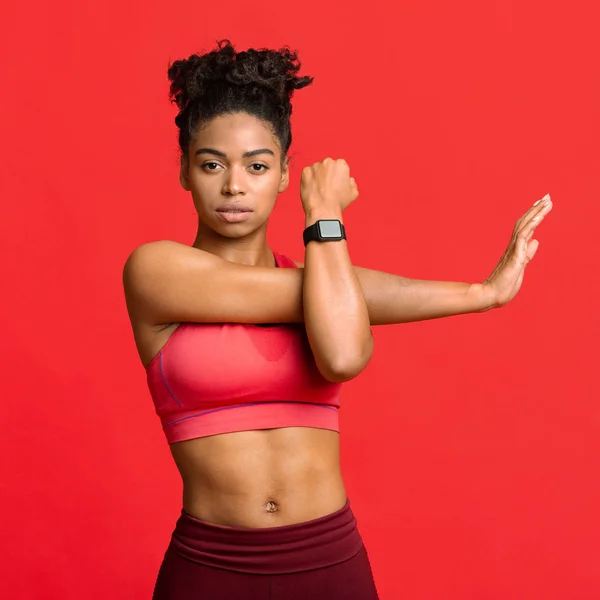 Joven chica deportiva haciendo ejercicios físicos sobre fondo rojo —  Fotos de Stock