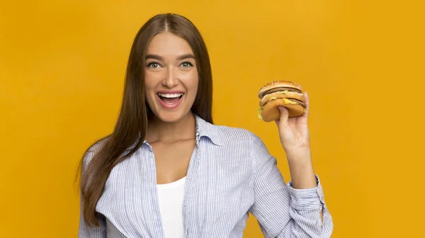 Allegro Lady Holding Burger in piedi su sfondo giallo Studio, Panorama — Foto Stock