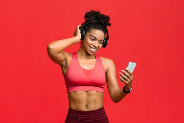 Menina fitness preto feliz escolhendo música no smartphone para se exercitar — Fotografia de Stock