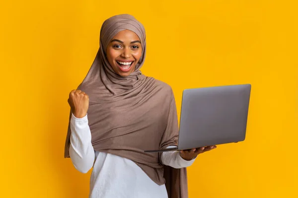 Alegre afro musulmán chica en la cabeza bufanda regocijo éxito con el ordenador portátil —  Fotos de Stock