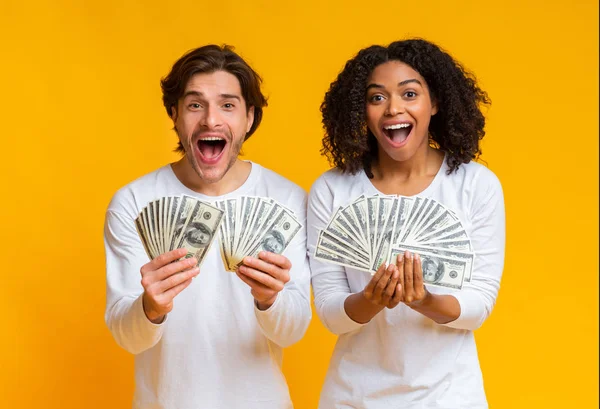 Alegre pareja interracial sosteniendo mucho dinero en efectivo y exclamando con alegría —  Fotos de Stock