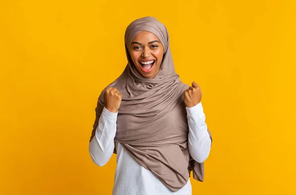 Mulher muçulmana preta em lenço de cabeça regozijando sucesso com punhos levantados — Fotografia de Stock