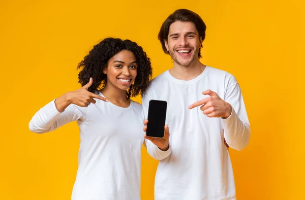 Lächelndes Paar hält modernes Smartphone mit schwarzem Bildschirm in der Hand — Stockfoto