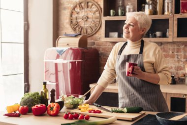 Mutlu emekli bayan, mutfakta kahve molası veriyor.