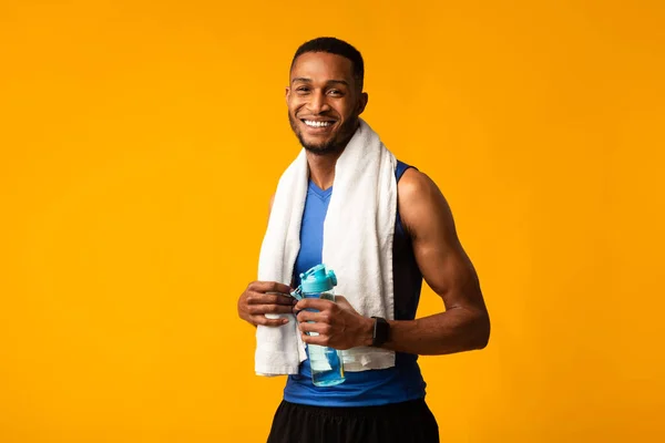 Красавчик афро-спортсмен держит бутылку с водой. — стоковое фото