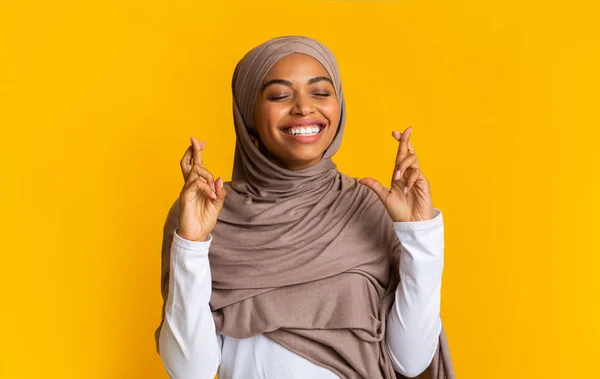 Mujer afro musulmana positiva en hiyab pidiendo deseo con los dedos cruzados — Foto de Stock