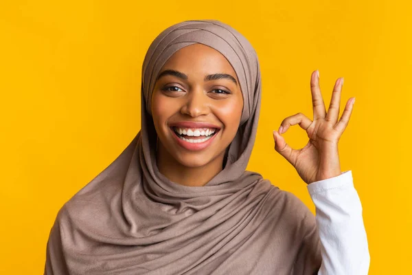 Gadis muslim hitam ceria dalam gerakan hijab ok pada latar belakang kuning — Stok Foto