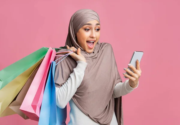 头戴头巾、头戴智能手机、头戴明亮购物袋的阿拉伯女孩震惊了 — 图库照片