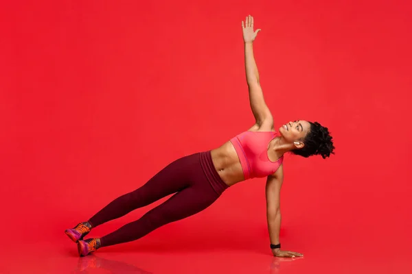 Mulher esportiva concentrada fazendo ioga sobre fundo vermelho — Fotografia de Stock