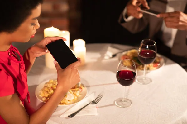 Casal milenar tirando foto de comida durante o jantar no restaurante — Fotografia de Stock