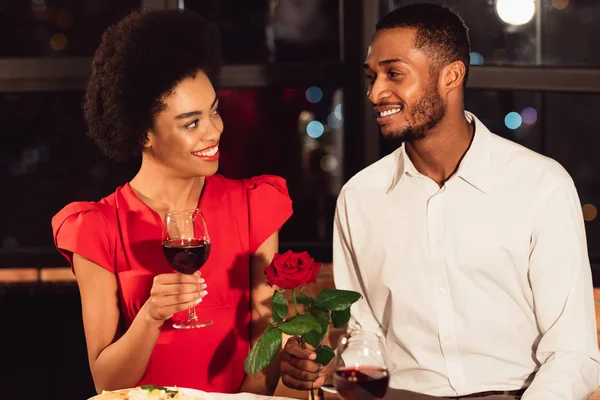 Freund schenkt Rose an glückliche Freundin, die im Restaurant Valentinstag feiert — Stockfoto